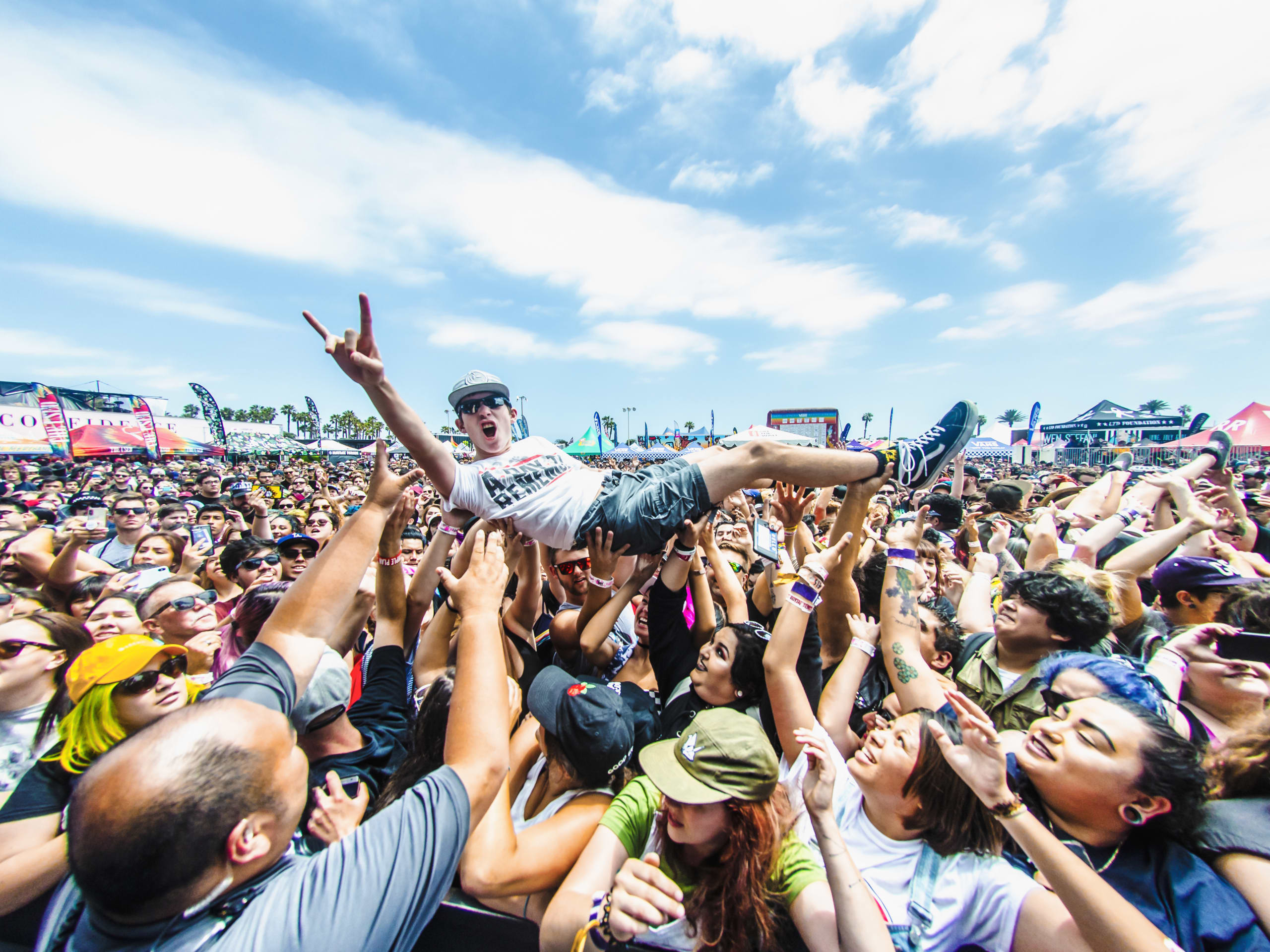 A man crowd surfing in a huge crowd at the Vans Warped Tour